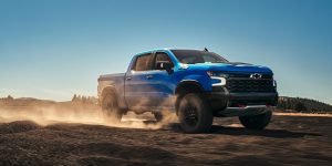The cutting-edge 2025 Chevy Silverado 1500 driving at high speeds on a dirt road.