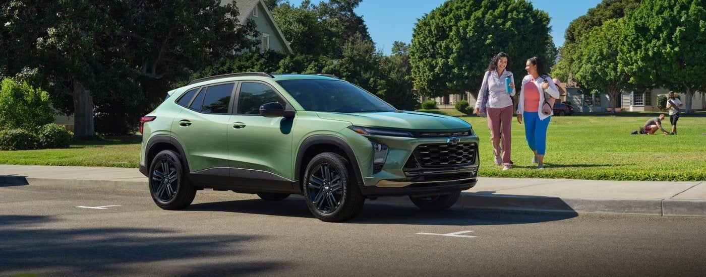 A green 2026 Chevy Trax ACTIV parked by a field and people.