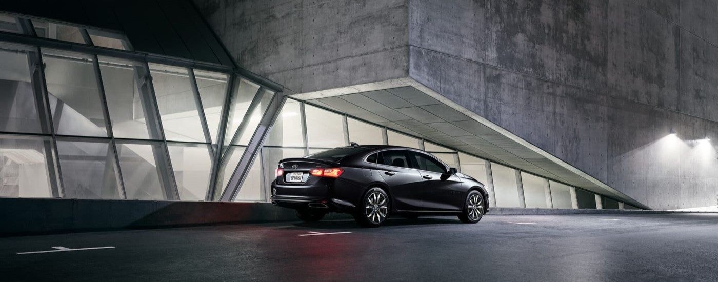 Black 2024 Chevy Malibu RS parked by a building.