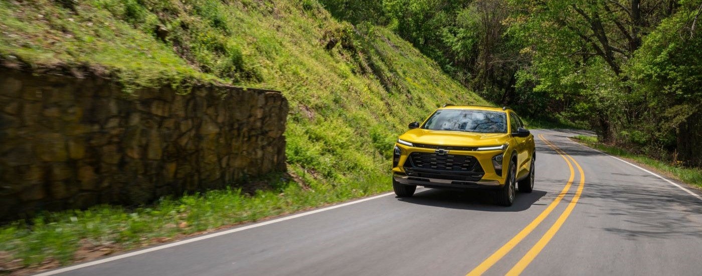 Yellow 2026 Chevy Trax ACTIV driving down a road.