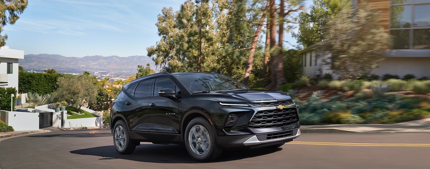 Black 2026 Chevy Blazer driving down a neighborhood street.