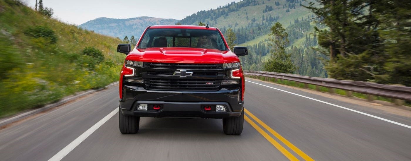 Red 2025 Chevy Silverado 1500 TrailBoss driving down a road.