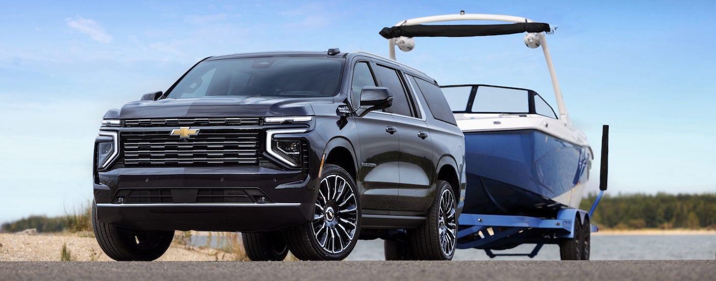 Black 2025 Chevy Suburban High Country towing a boat.
