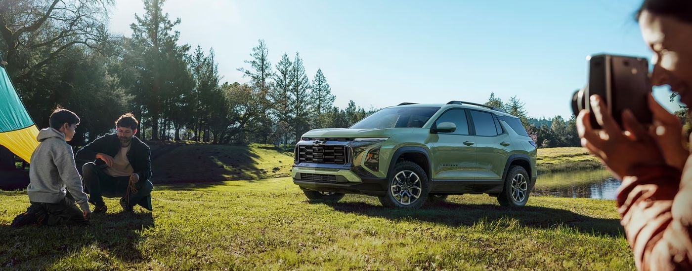 Person taking photos near a green 2026 Chevy Equinox ACTIV