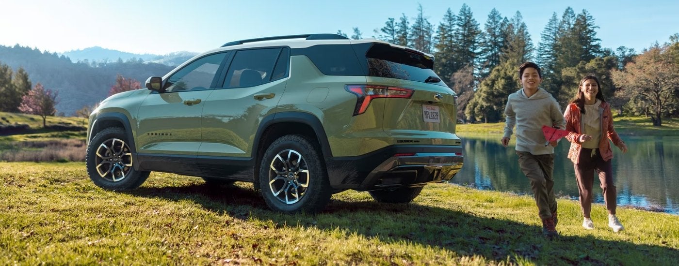 Kids playing near a green 2026 Chevy Equinox ACTIV