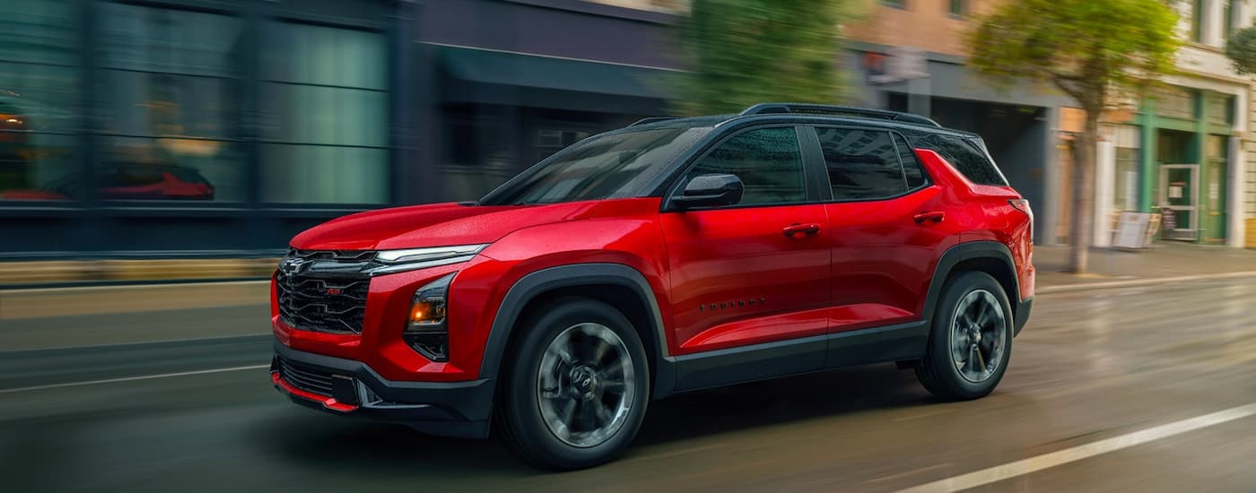 Red 2026 Chevy Equinox RS driving down a city street.
