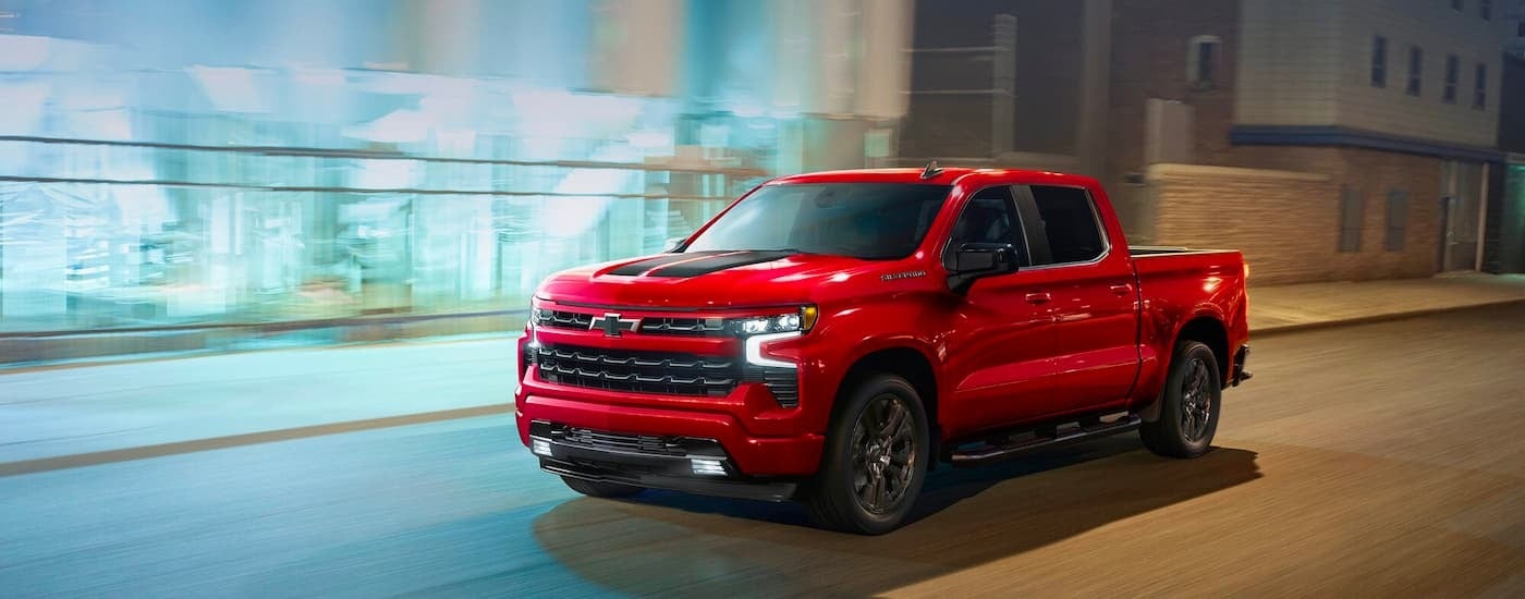 Red 2026 Chevy Silverado 1500 RST driving down a city street.