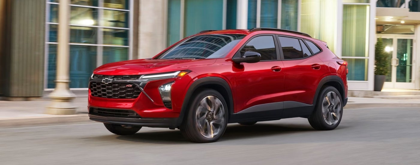 Red 2026 Chevy Trax 2RS driving down a city street.