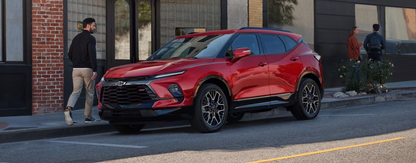 Red 2026 Chevy Blazer parked on a street with a man walking away.