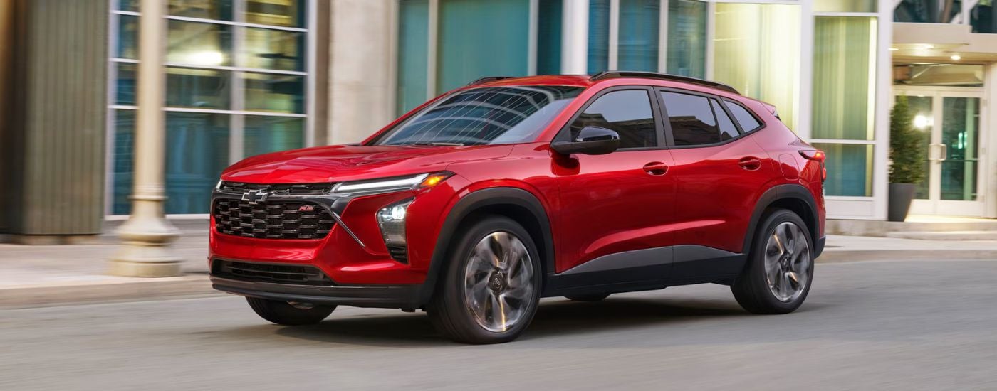 Red 2026 Chevy Trax driving on a city street.