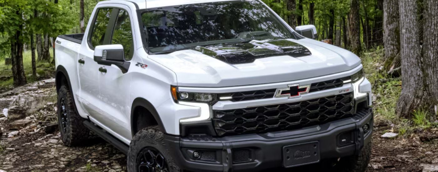 White 2026 Chevy Silverado LD driving in a forest.