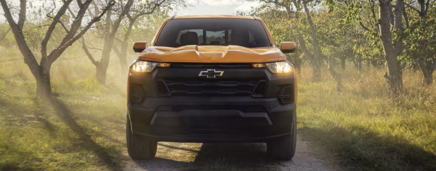Front view of a yellow 2026 Chevy Colorado driving through the woods.