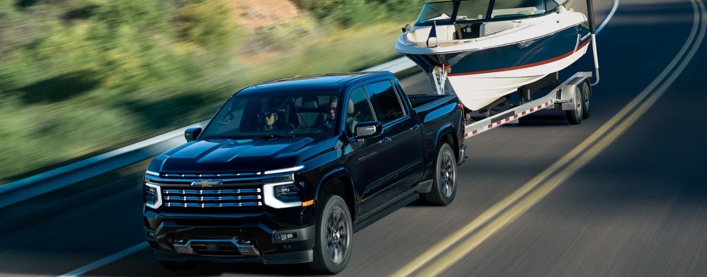 A black 2027 Chevy Silverado 1500 High Country towing a boat.