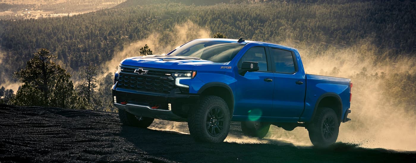 Blue 2025 Chevy Silverado 1500 ZR2 driving up a dirt hill.